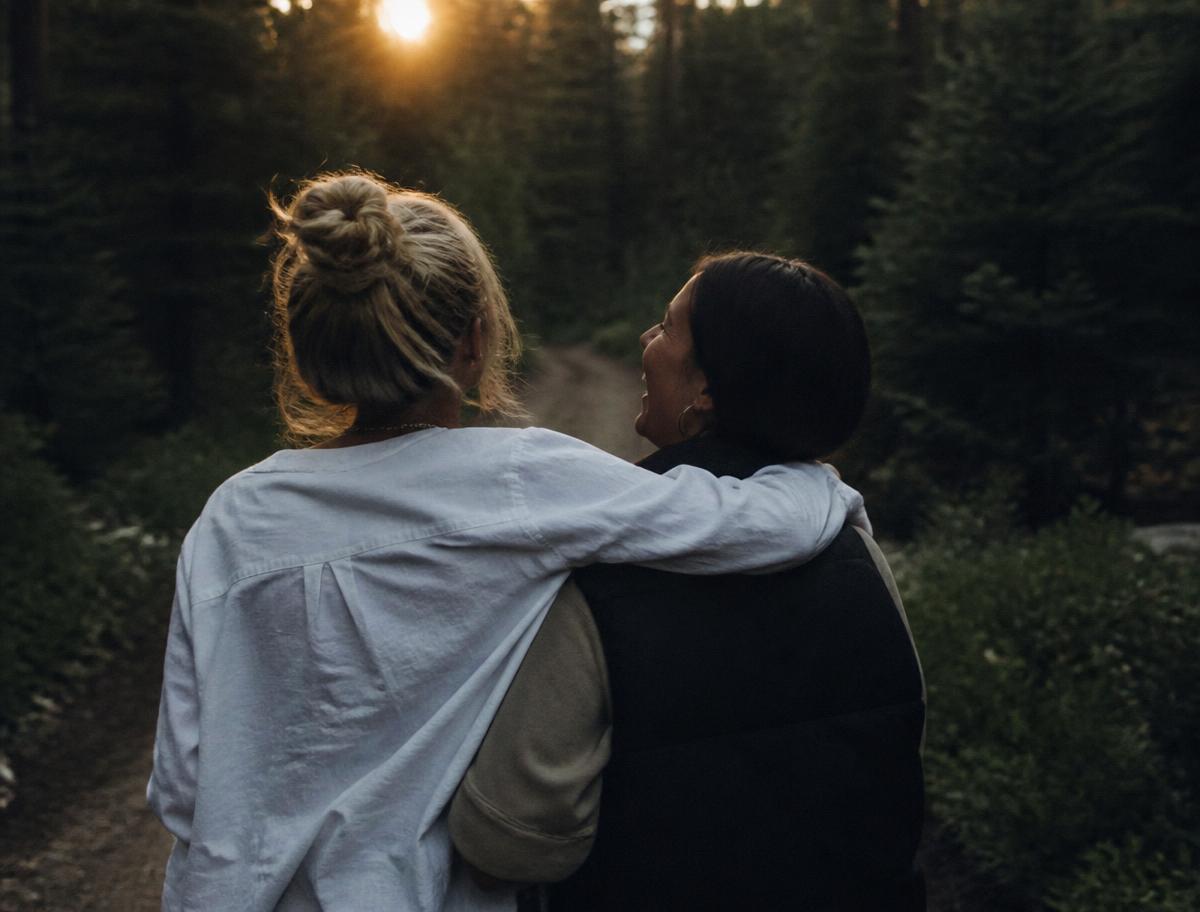 Two women walking arm in arm in the forest
