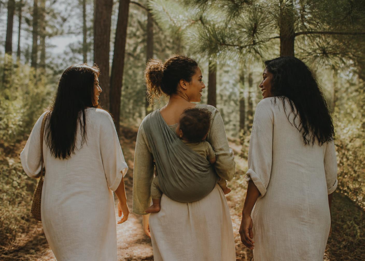 Three mothers walking and laughing together on a forest trail